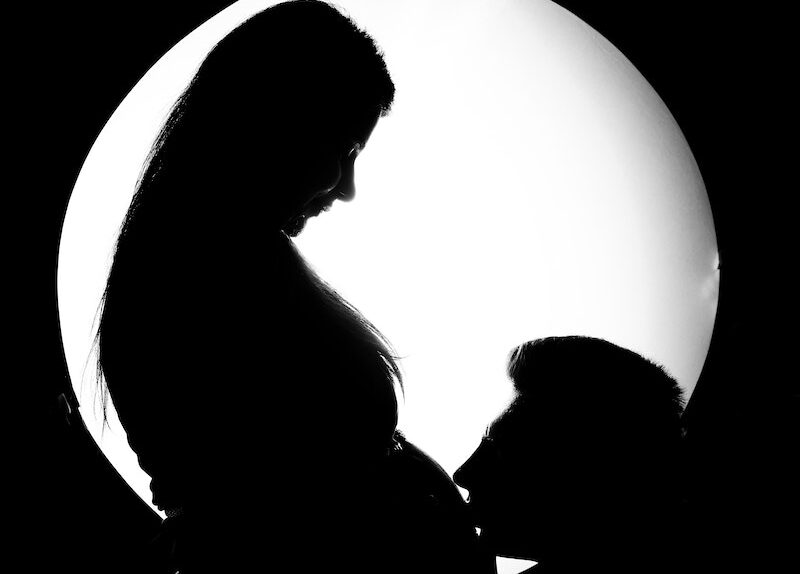 Silhouette of a Man Kissing the Tummy of a Pregnant Woman