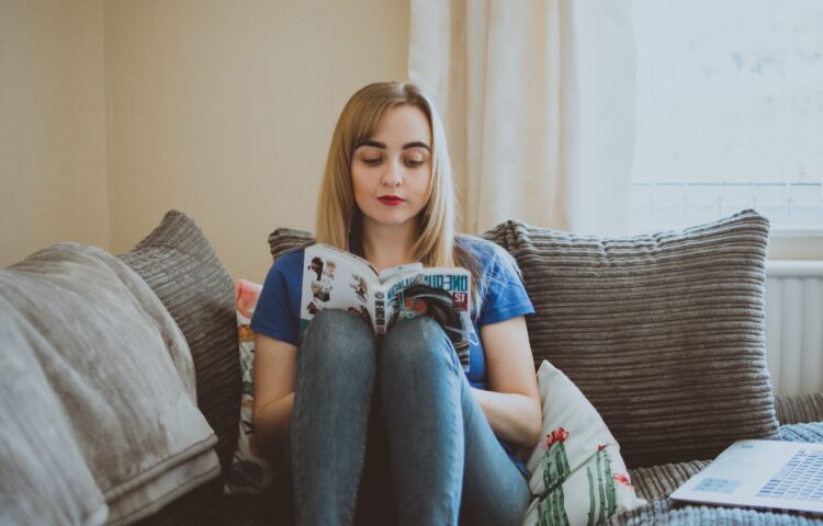 Woman Sitting On Couch While Reading A Book