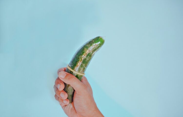 A Person Holding a Cucumber with Condom
