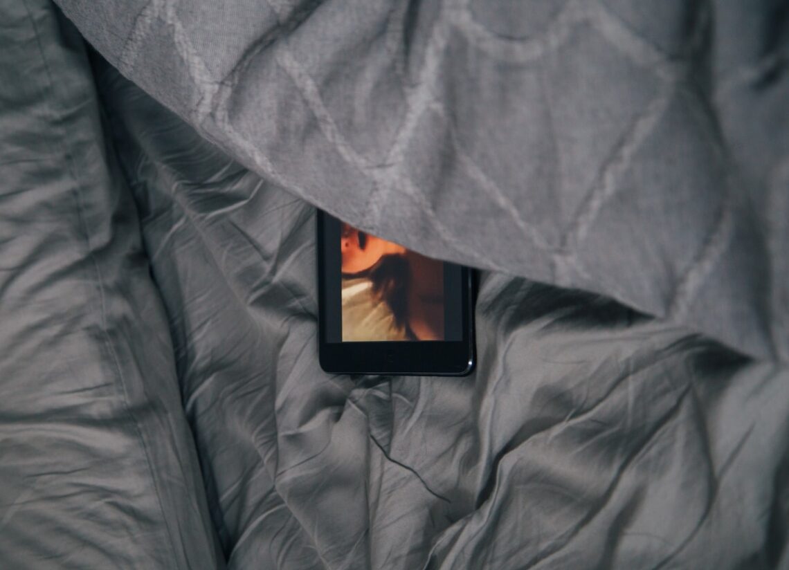 black Android smartphone on gray bed sheet